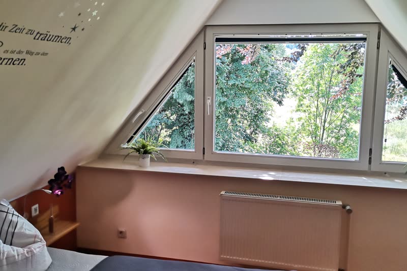 Schlafzimmer mit großem Dreiecksfenster und Blick ins Grüne