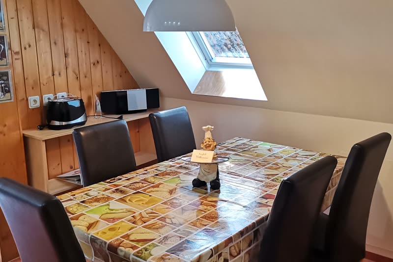 Esstisch mit vier schwarzen Lederstühlen unter einem Dachfenster