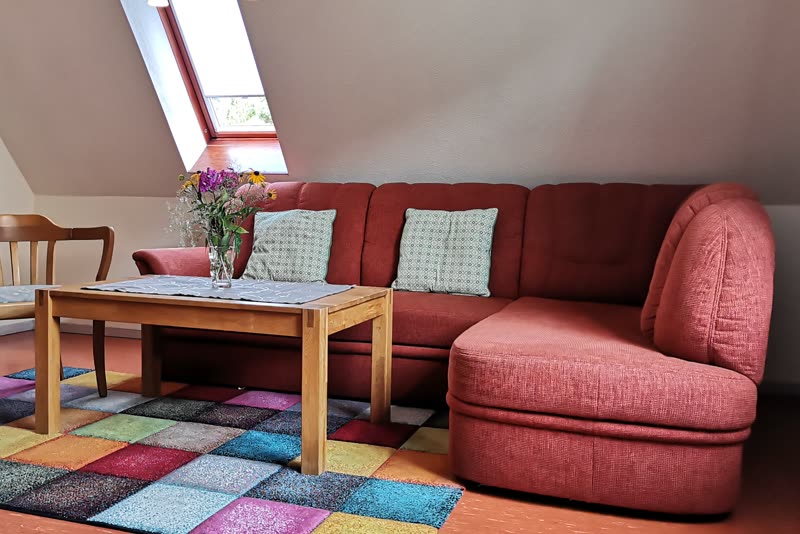 Rotes Ecksofa mit Couchtisch, buntem Teppich und Dachfenster